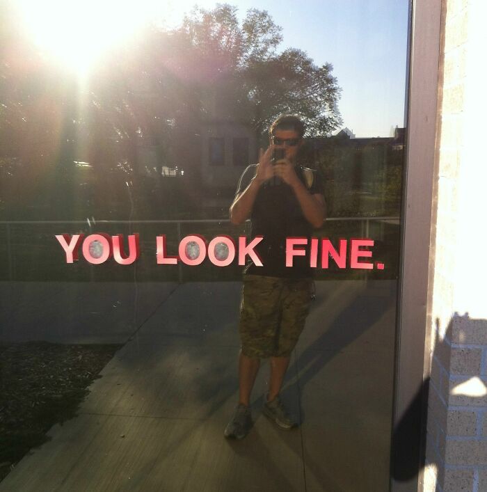 Man taking picture of a nice message on a mirror wall 