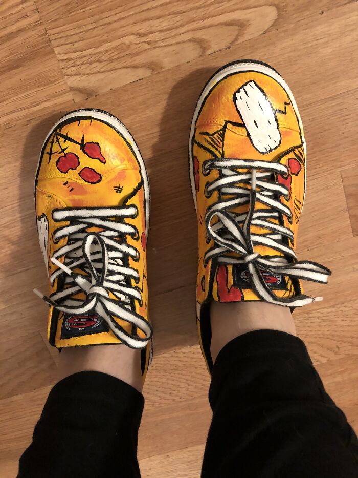 Colorful, hand-painted shoes with abstract designs on a wooden floor, showcasing a pair of unique footwear.