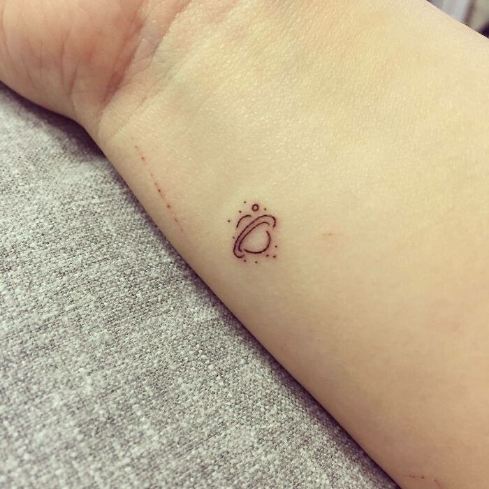 Small Saturn tattoo on wrist