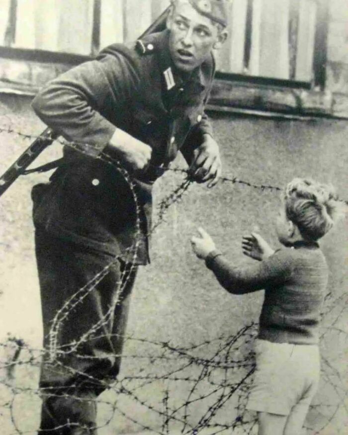 Un soldado de Alemania Oriental ayuda a un niño a cruzar el Muro de Berlín el día que se erigió en 1961