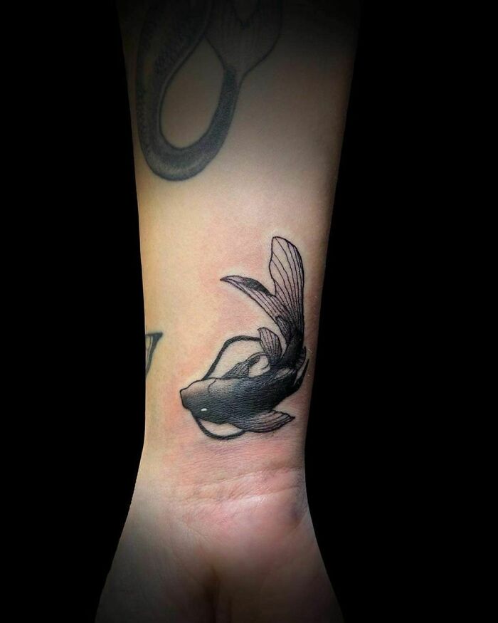 Little black Koi fish tattoo on wrist