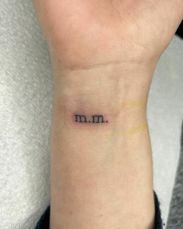 Minimalist wrist tattoo with "m.m." initials, showcasing a stylish accessory idea.
