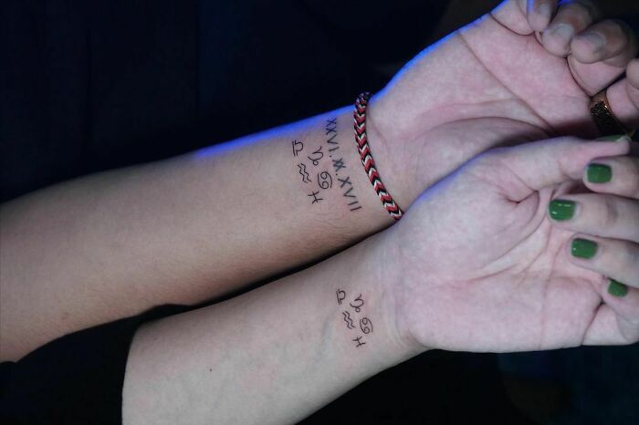 Two wrists with zodiac symbol tattoos, showcasing stylish wrist tattoo ideas.