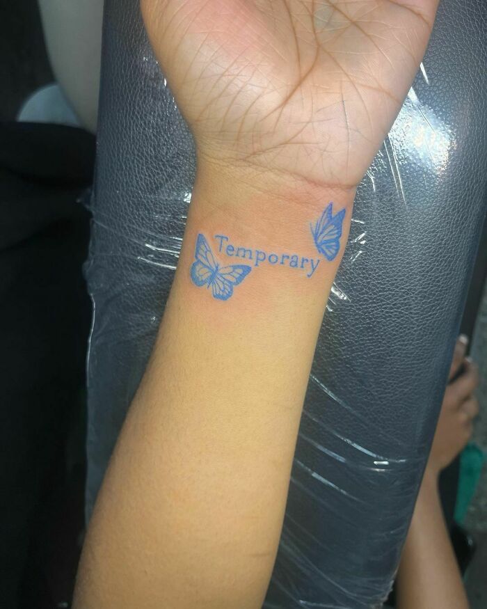 Word and butterflies tattoo on wrist in blue color