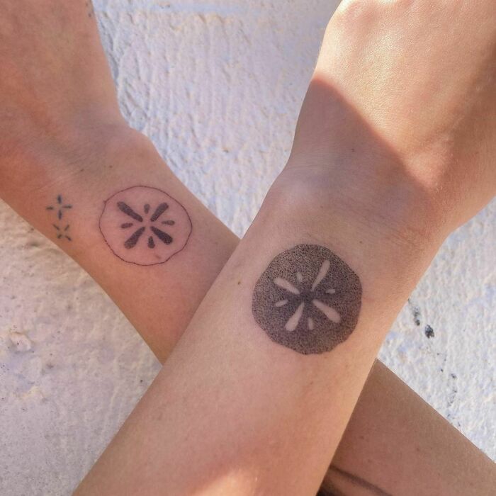 Two wrists with sand dollar tattoos, showcasing a stylish wrist tattoo design.