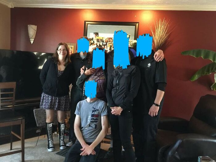 Person wearing unique tall black boots with white laces, surrounded by friends in a cozy living room setting.