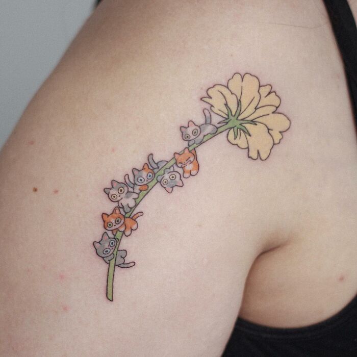 Animal-themed tattoo design with cute kittens on a flower stem on someone's arm.