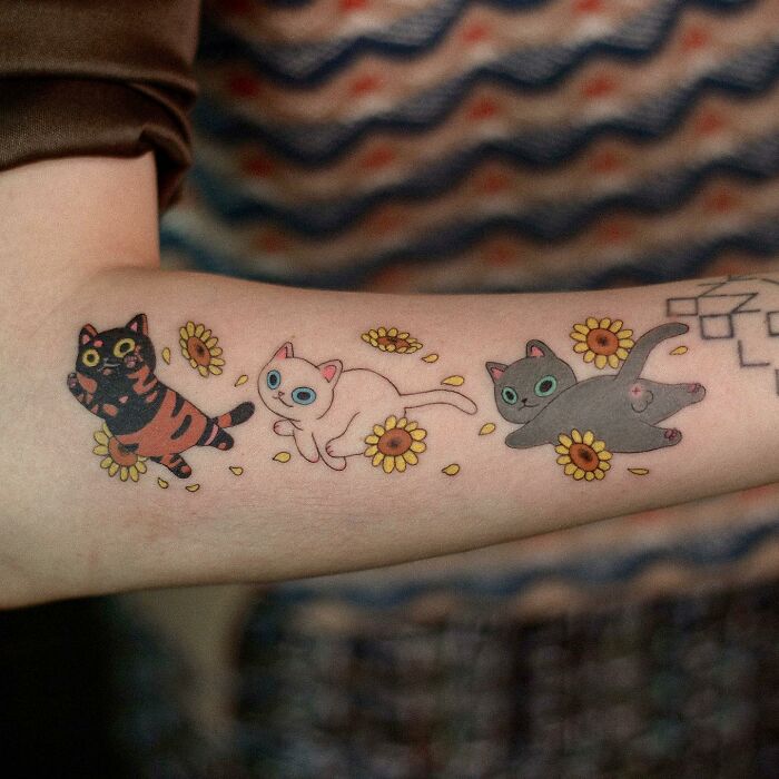 Animal-themed tattoo design featuring playful cats and flowers on a person's arm.