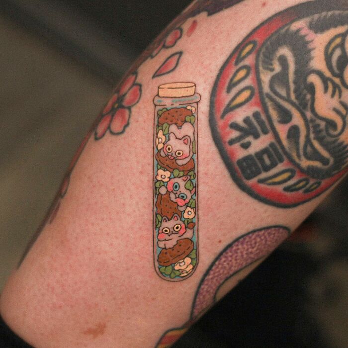 Adorable animal-themed tattoo design featuring cartoon animals in a test tube on arm.