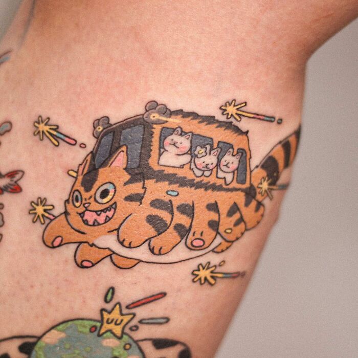 Adorable animal-themed tattoo design featuring a smiling cat bus with passengers.
