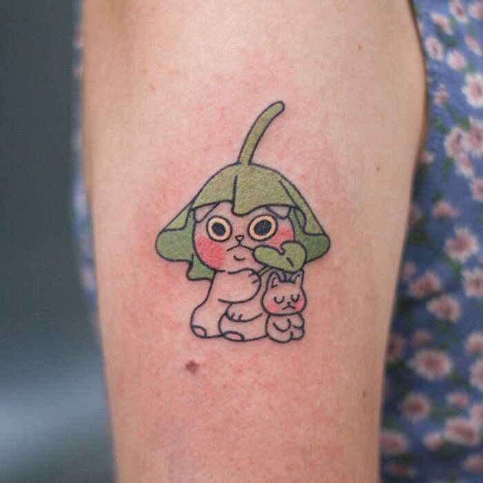 Adorable animal-themed tattoo featuring a cute cartoon creature with a leaf hat on an arm.