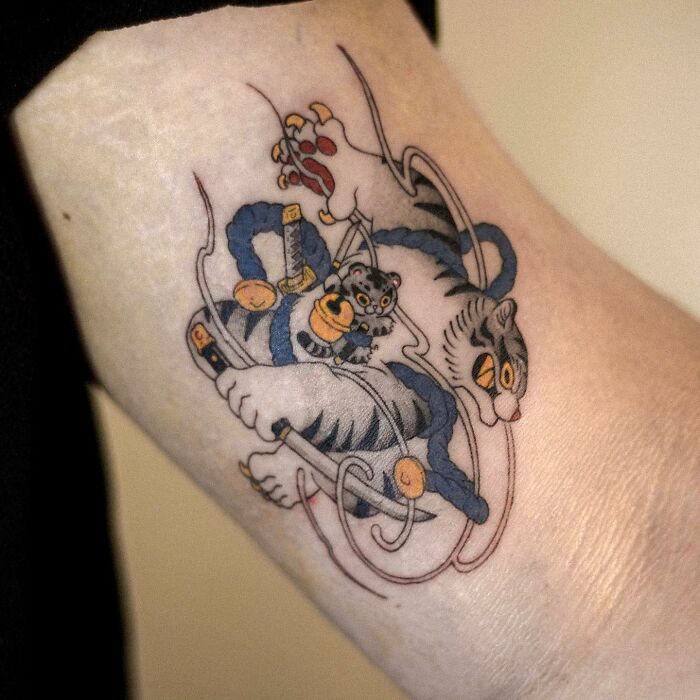 Adorable animal-themed tattoo of playful tigers on forearm.