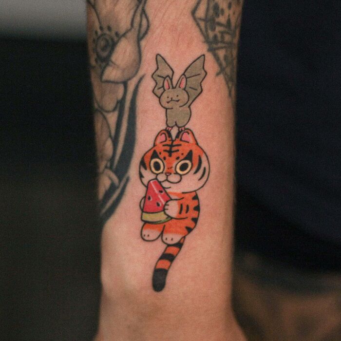 Tattoo of a cute tiger holding watermelon with a bat on top, showcasing animal-themed designs.