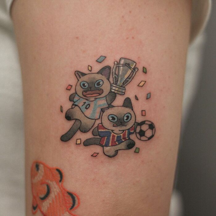 Adorable animal-themed tattoo of cats playing soccer with confetti.