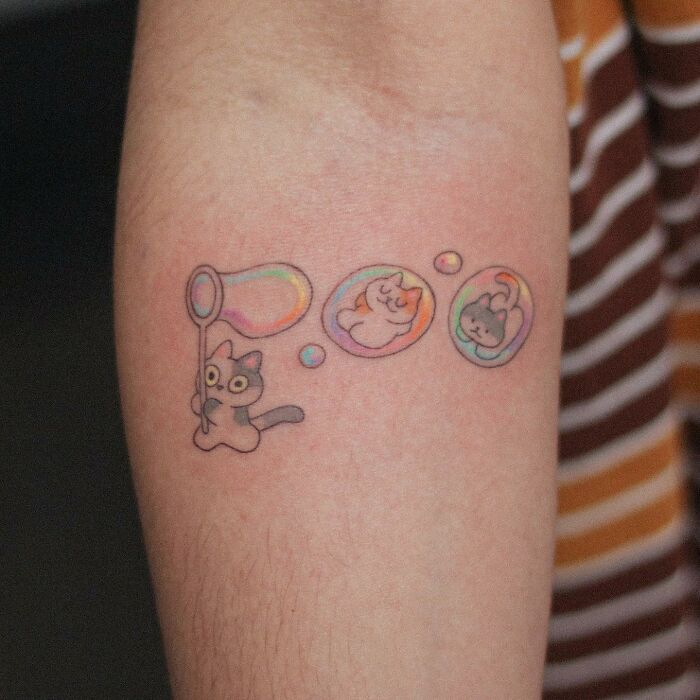 Adorable animal-themed tattoo with a cat blowing bubbles containing sleeping creatures.