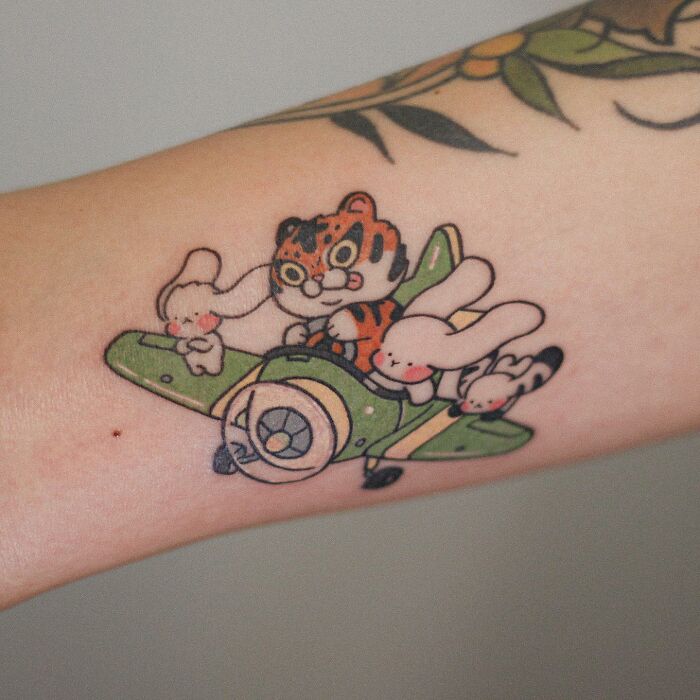Adorable animal-themed tattoo of a tiger and bunnies on a green plane.