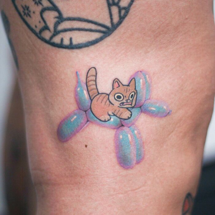 Tattoo of a cute cat on a blue balloon animal, showcasing the artist's adorable animal-themed designs.