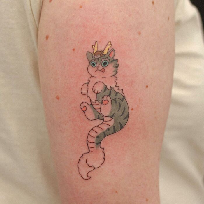 Adorable animal-themed tattoo of a cute cat with antlers on the arm.