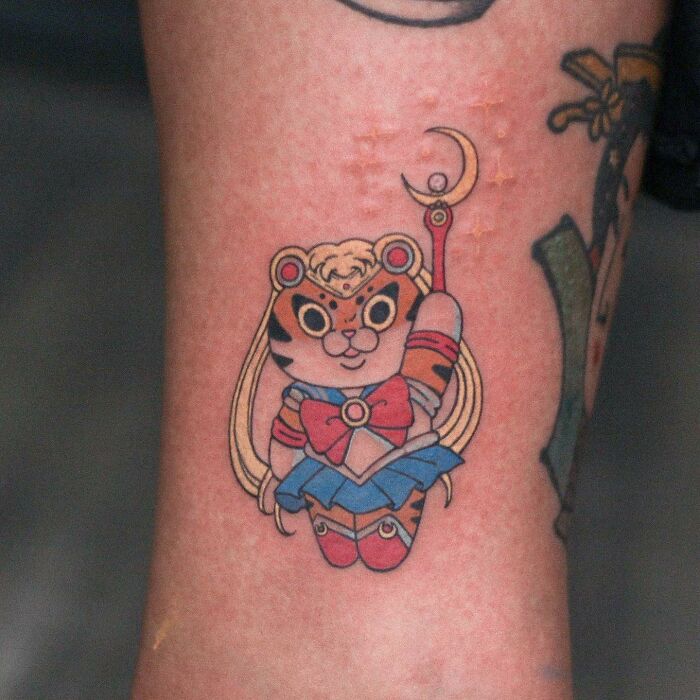 Adorable animal-themed tattoo of a cute character in sailor attire on arm.