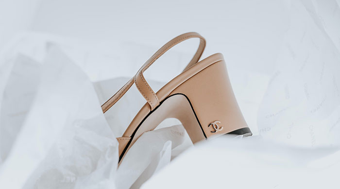 a pair of beige high heeled shoes sitting on top of a white sheet