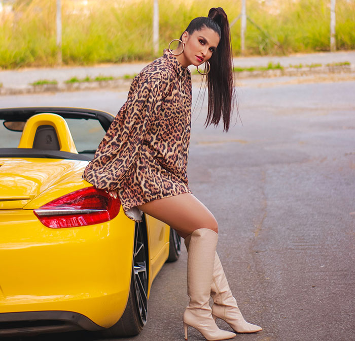 Woman in lion print dress posing near yellow car