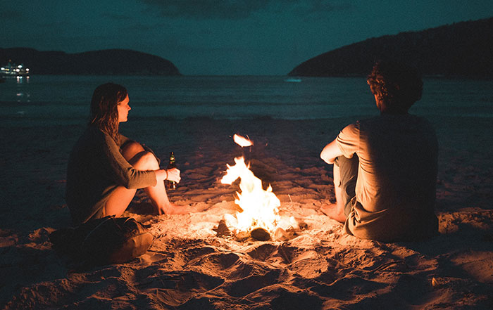 Friends sitting near bonfire at the beach