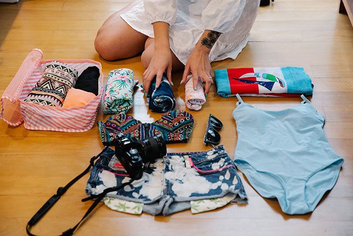 Woman packs her clothes and swimsuits