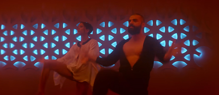 A couple dancing from Ex Machina and blue LED lights on the wall in their background
