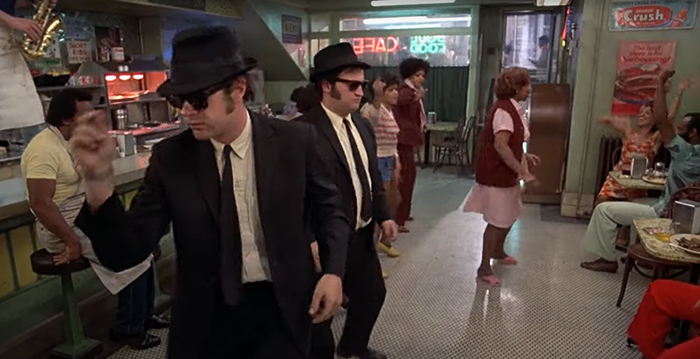 Jake, Elwood, Aretha, and other characters from The Blues Brothers dance in the restaurant