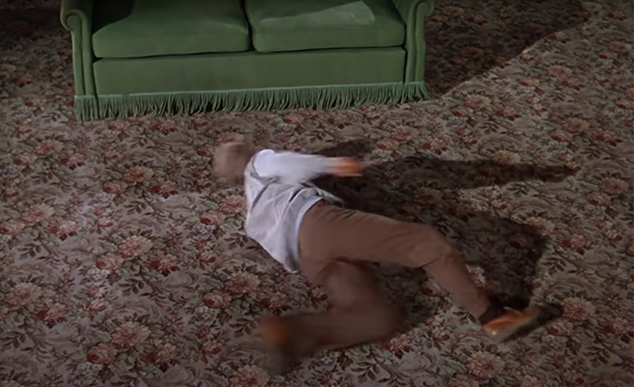 Donald O'Connor dancing on the floor with carpet and green sofa near him