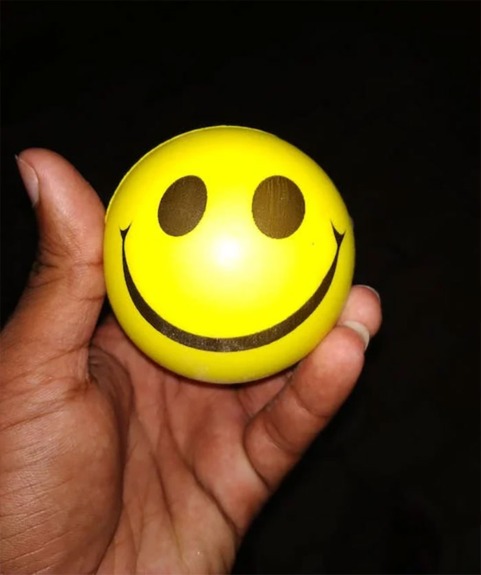 Person holding yellow emoticon ball