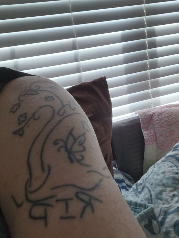 Arm tattoo featuring floral designs and a butterfly, with the letters "RIP" visible.