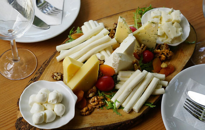 different kinds of cheese with walnuts and cherry tomatoes on a wooden board