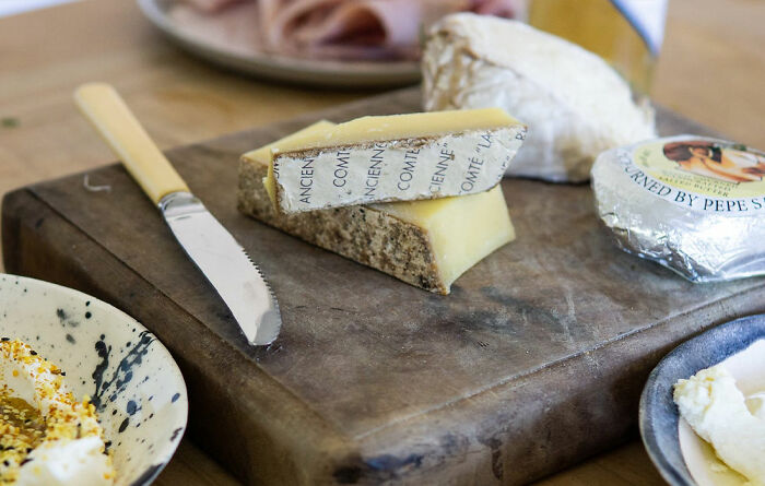 different kinds of cheese near the knife on a wooden board