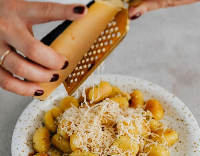 woman grating cheese on potatoes