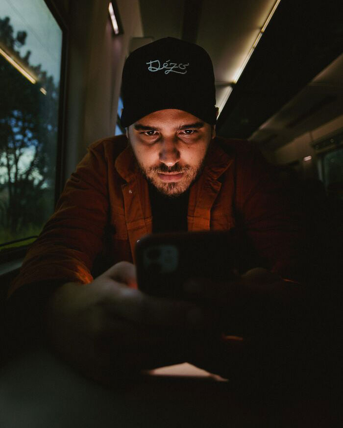 Man Scrolling On Mobile Phone In Dark Train 
