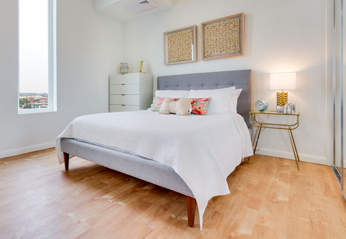 Modern bedroom with creative decoration, featuring gray bed, colorful pillows, and elegant side table with lamp.