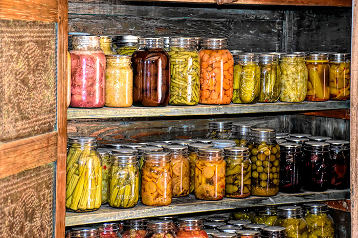 A wooden shelf filled with lots of jars of preserve food