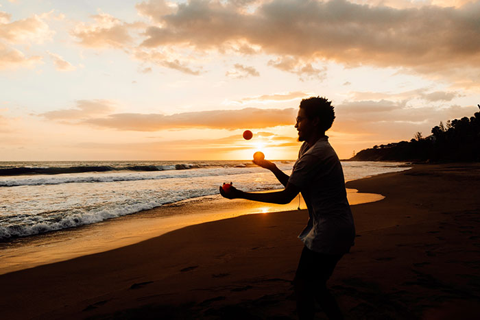 Man juggling on beach during sunset