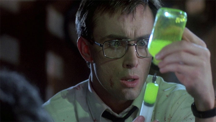 Herbert West holding a syringe with green liquid 