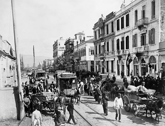 A View Showing The Business District Of Smyrna. Photograph Showing Horse Drawn Carts And Trolleys On A Busy Street In The Izmir Business District