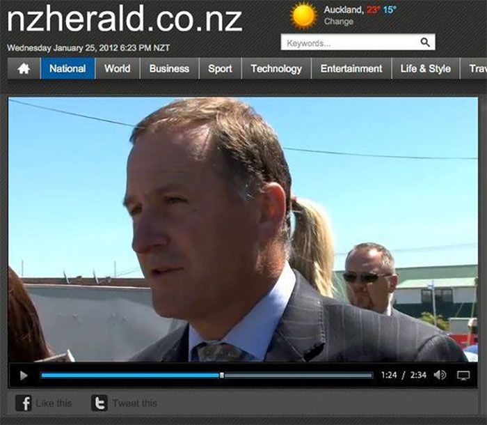 John Key, The Former New Zealand Prime Minister With Some Women With A Ponytail Standing Behind Him