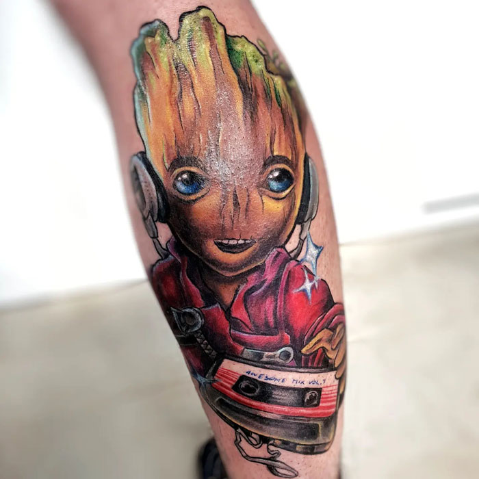 Marvel tattoo of Groot with headphones and a cassette player, showcasing colorful and detailed body art.