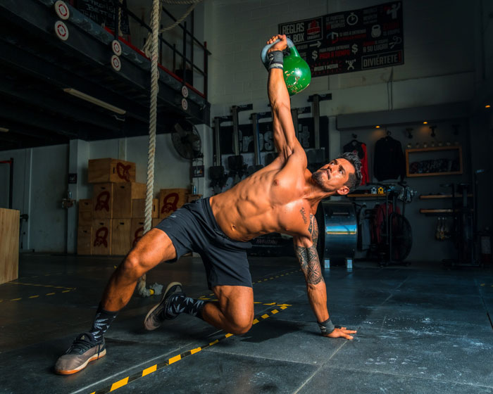 Man working out in a gym with a kettlebell, demonstrating strength and fitness.
