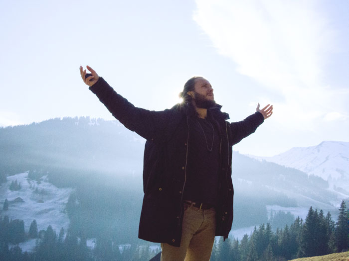 Man with arms wide open in snowy mountain setting, embodying millennial slang vibes.