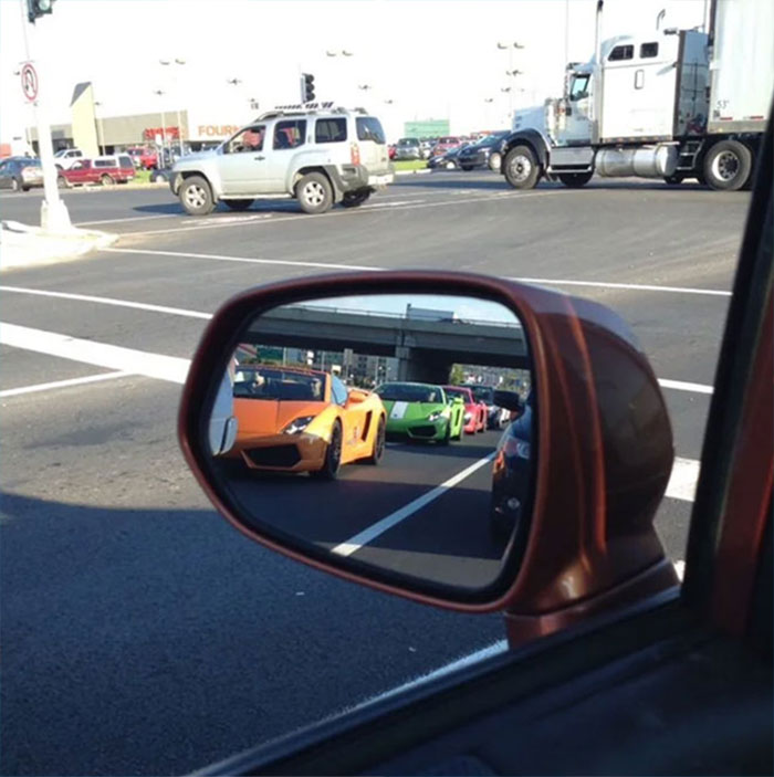 Multiple super cars seen in a car mirror's reflection