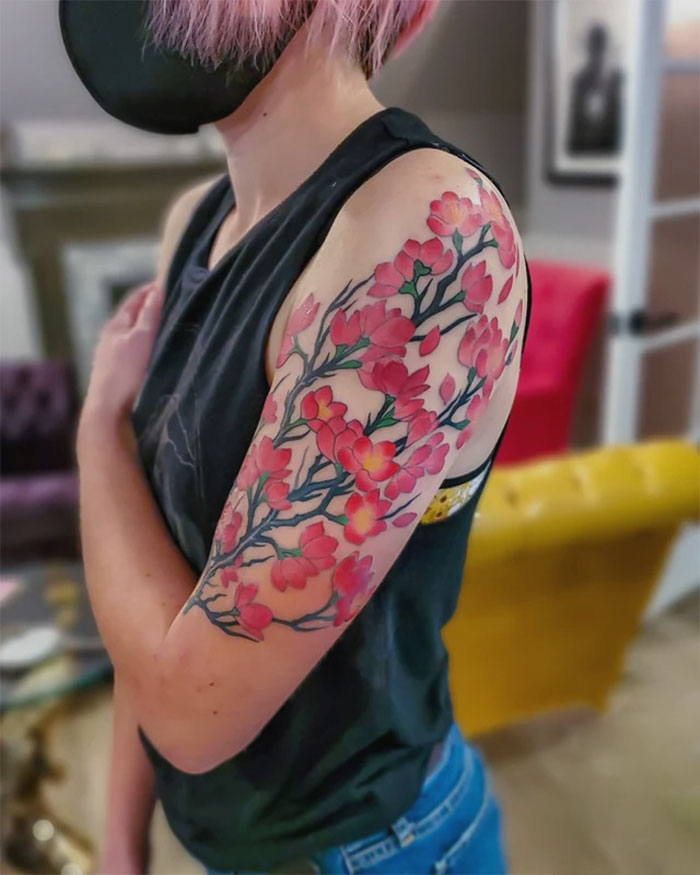 Person with a vibrant, floral nature tattoo sleeve in pink and green.
