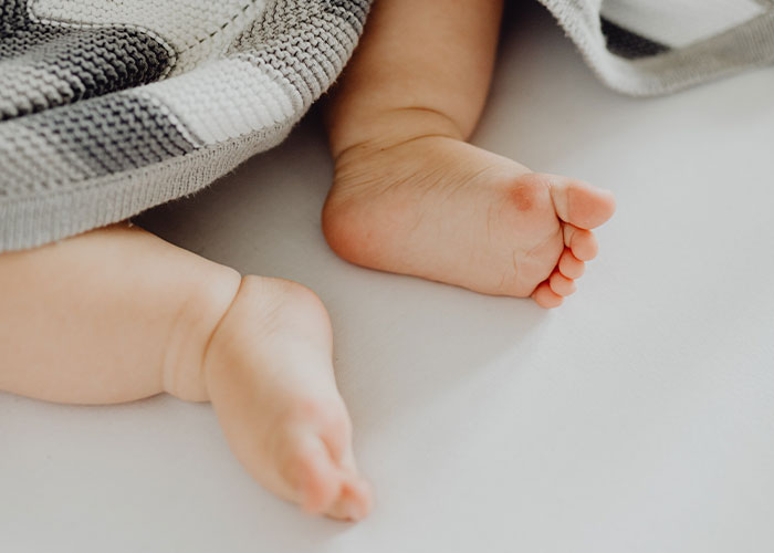 Baby's feet peeking from under a blanket, symbolizing grandkid's footprint. Baby's feet peeking from under a blanket, symbolizing grandkid's footprint.