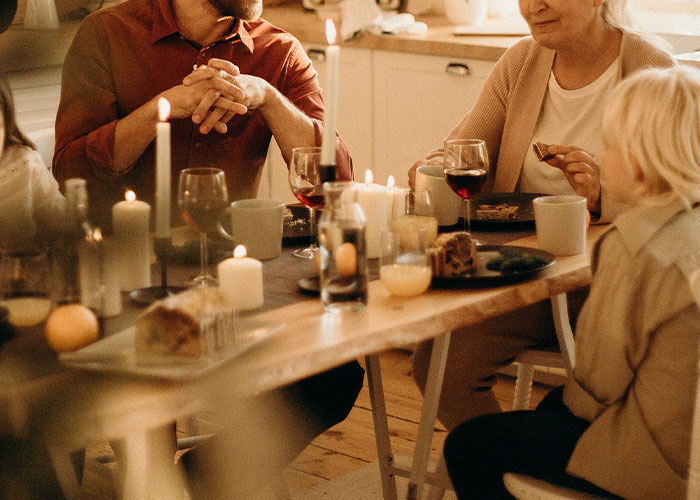 Family dinner scene with candles and food, discussing a grandmother's desire for a tattoo of her grandkid's footprint. Family dinner scene with candles and food, discussing a grandmother's desire for a tattoo of her grandkid's footprint.