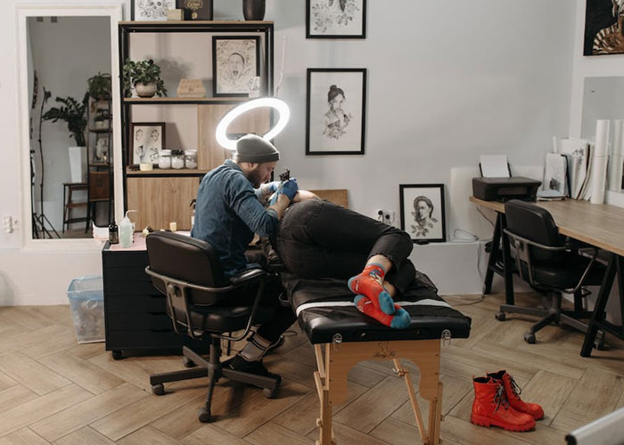 Tattoo artist working in a studio, tattooing a footprint on a client's arm, surrounded by art and equipment. Tattoo artist working in a studio, tattooing a footprint on a client's arm, surrounded by art and equipment.